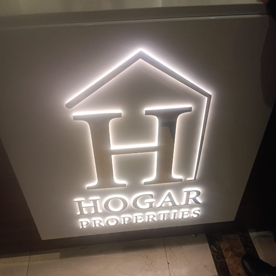 HOGAR PROPERTIES backlit reception sign with white halo glow behind house outline and letter H mounted on office wall