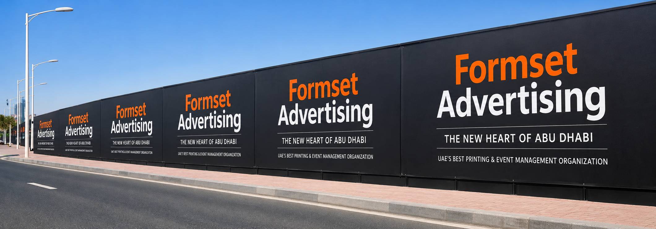 A large black advertising hoarding panel with orange and white text reading 'Formset Advertising' and additional white text below, photographed outdoors against a blue sky with a paved road in the foreground.